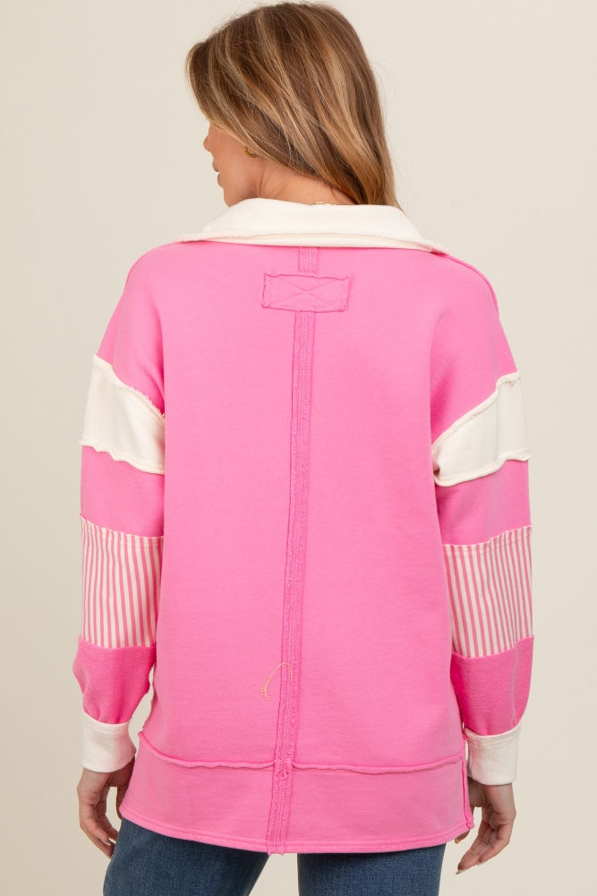 woman wearing a pink maternity sweatshirt with white and striped color block details, showing the back view