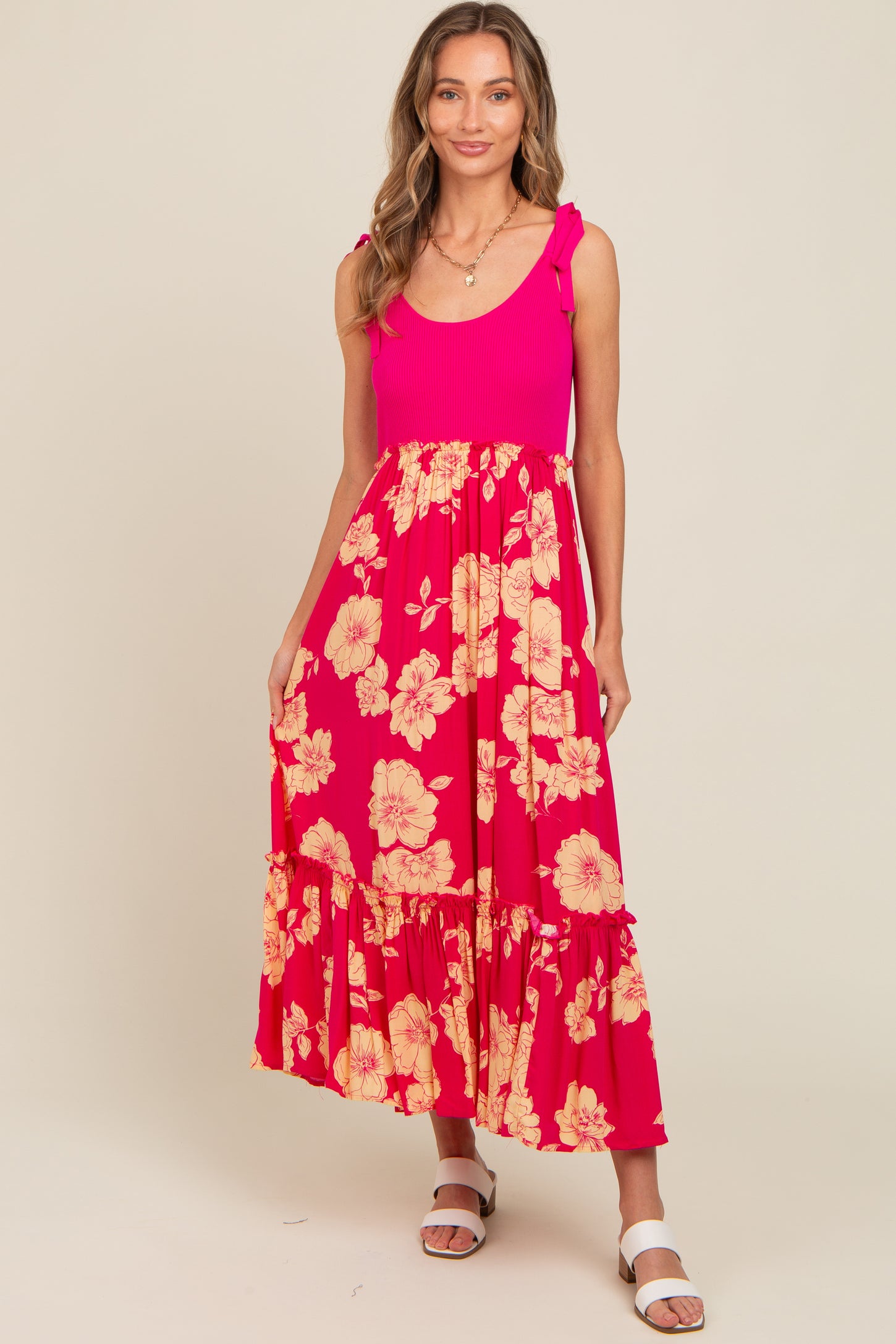 woman wearing a pink floral maxi dress with ruffled skirt and shoulder ties
