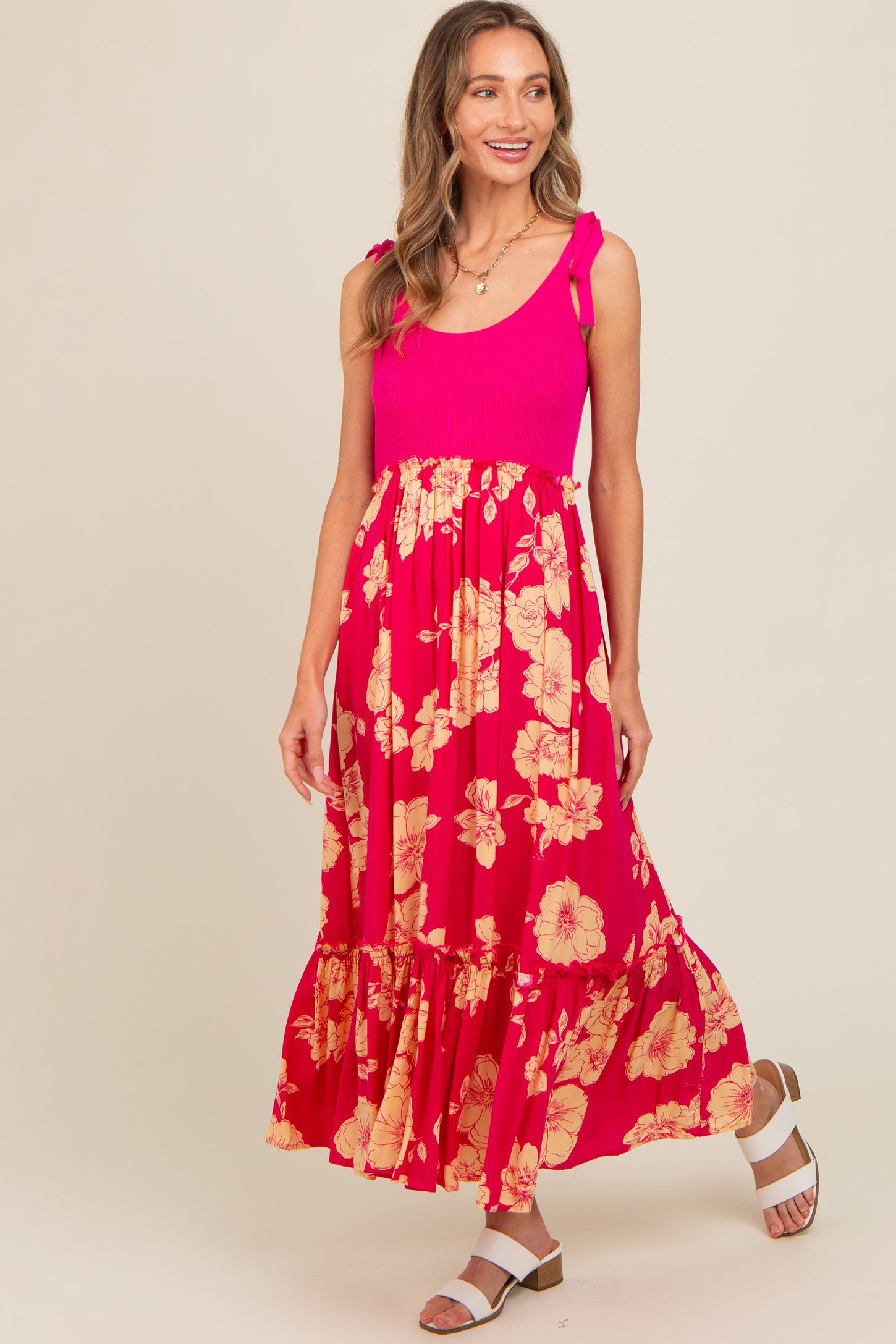 woman wearing a pink ribbed tank dress with floral skirt and ruffled hem, posing and smiling