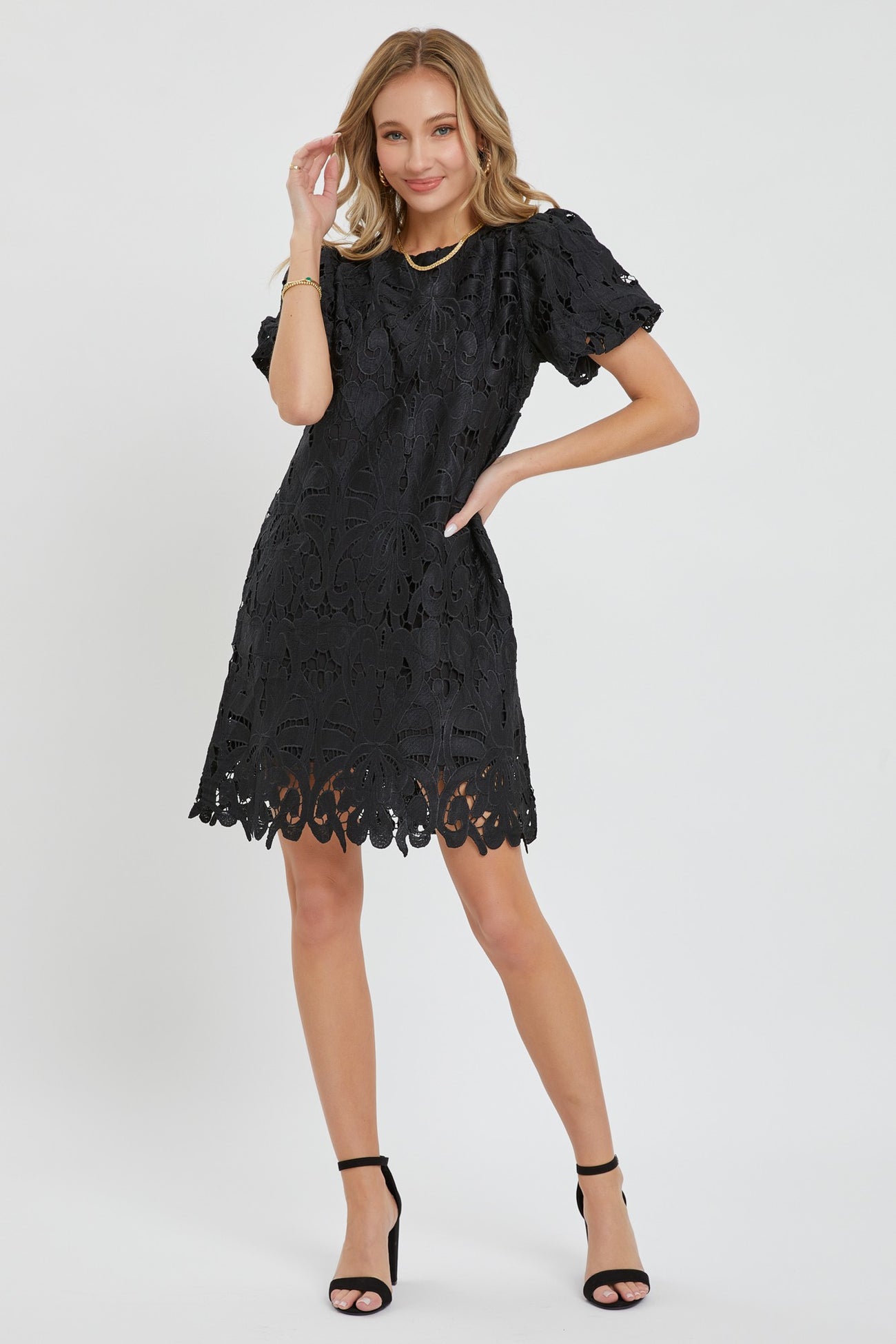 woman wearing a black lace short sleeve dress with a scalloped hem and a fitted silhouette