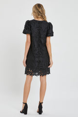 woman wearing a black lace short sleeve dress with a scalloped hem and back zipper detail