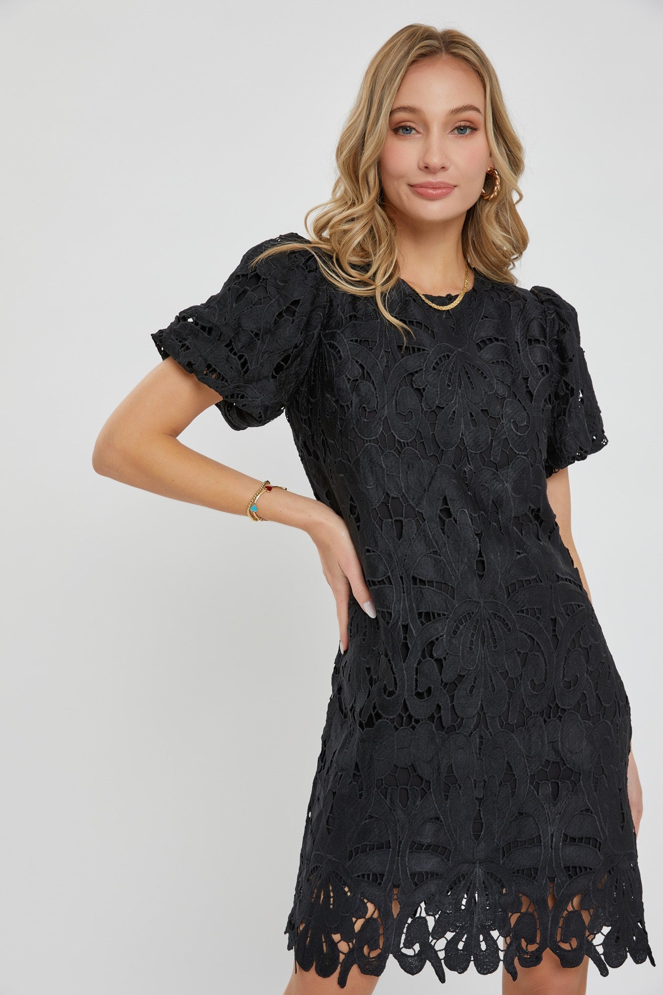 woman wearing a black short sleeve lace dress with floral patterns and a scalloped hemline