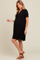 woman wearing a short sleeve black maternity dress with a relaxed fit and side slits, showing her baby bump