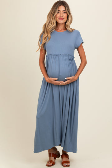 woman wearing a teal maternity maxi dress with a gathered waist and holding her baby bump