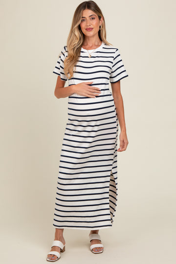 woman wearing a striped maternity maxi dress with short sleeves and a side slit, cradling her baby bump