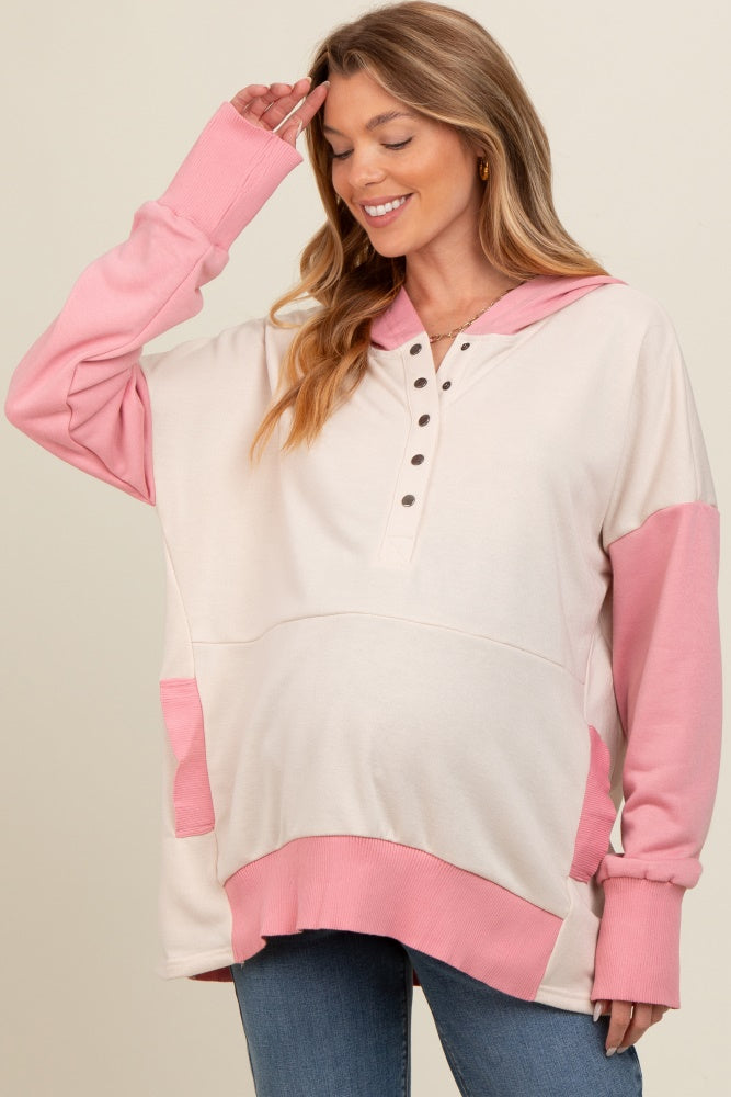 woman wearing a cream and pink oversized maternity hoodie with button detail and a visible baby bump