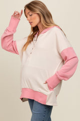 woman wearing a cream and pink oversized maternity hoodie with a baby bump visible