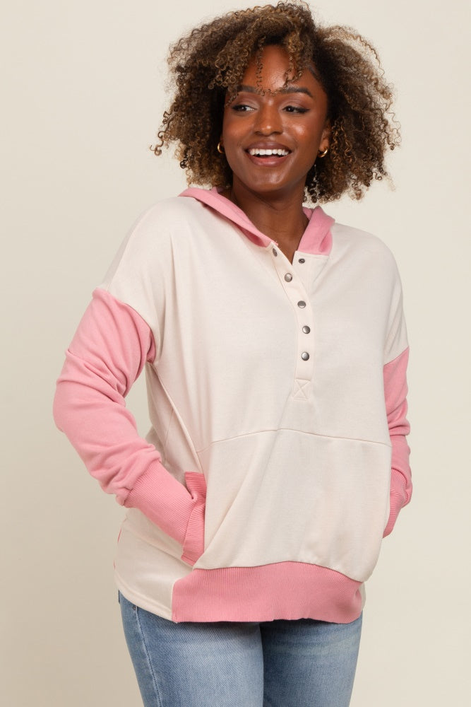 woman wearing a cream and pink colorblock hoodie with a button placket and front pockets