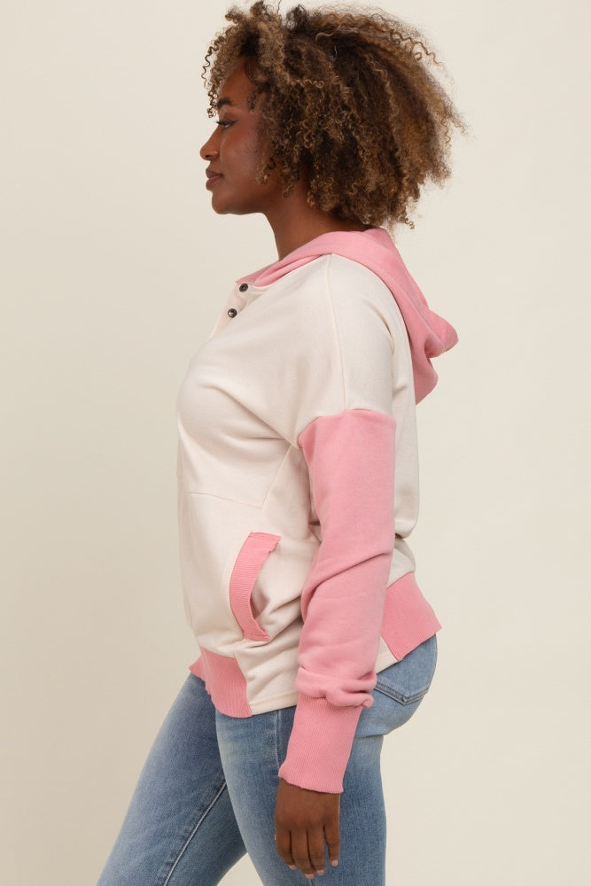woman wearing a light pink and cream color block hoodie with a kangaroo pocket and denim jeans