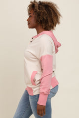 woman wearing a light pink and cream color block hoodie with a kangaroo pocket and denim jeans