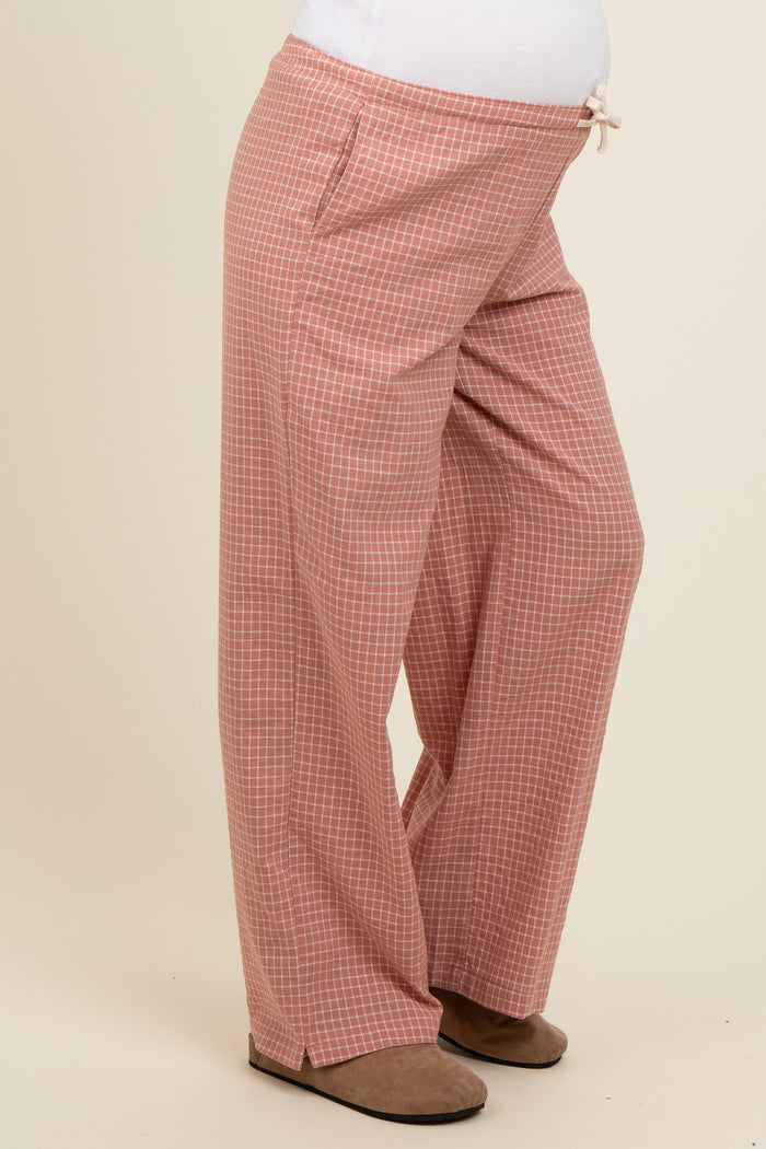 woman wearing light pink checkered maternity pants with pockets and a drawstring waist, showing her baby bump