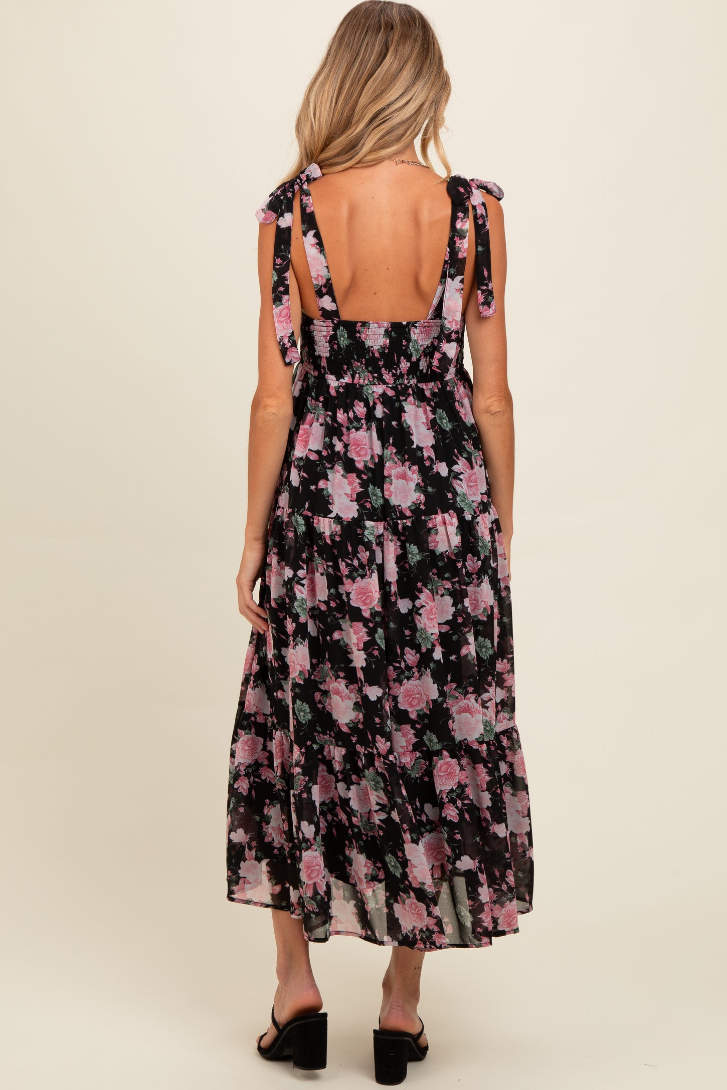 woman wearing a black floral maternity maxi dress with tie straps and a smocked back