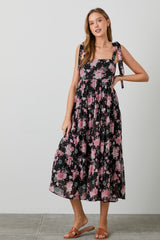 woman wearing a black floral maxi dress with tie straps and a flowy skirt