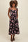 woman wearing a black floral midi dress with adjustable shoulder straps and pockets