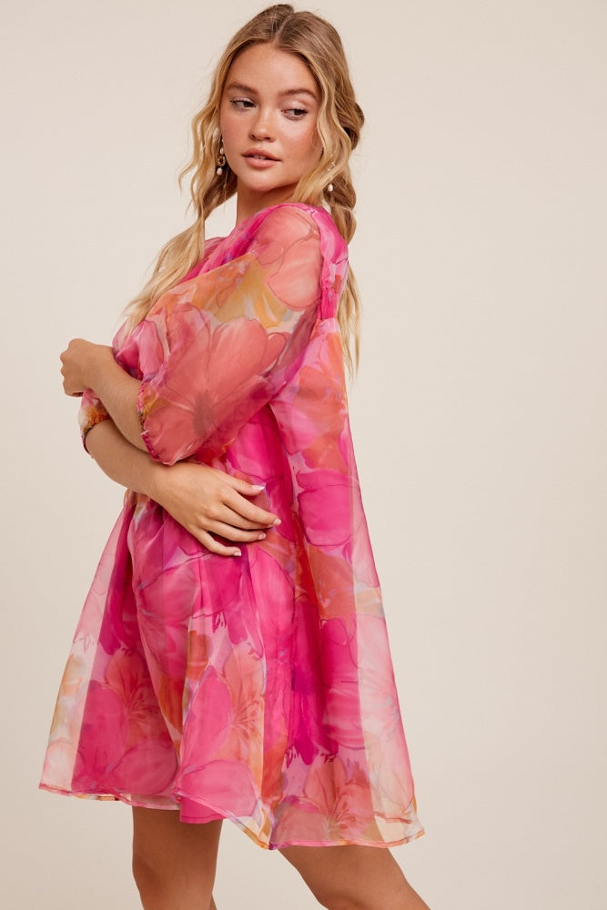 woman wearing a pink floral sheer dress with puff sleeves and a relaxed fit