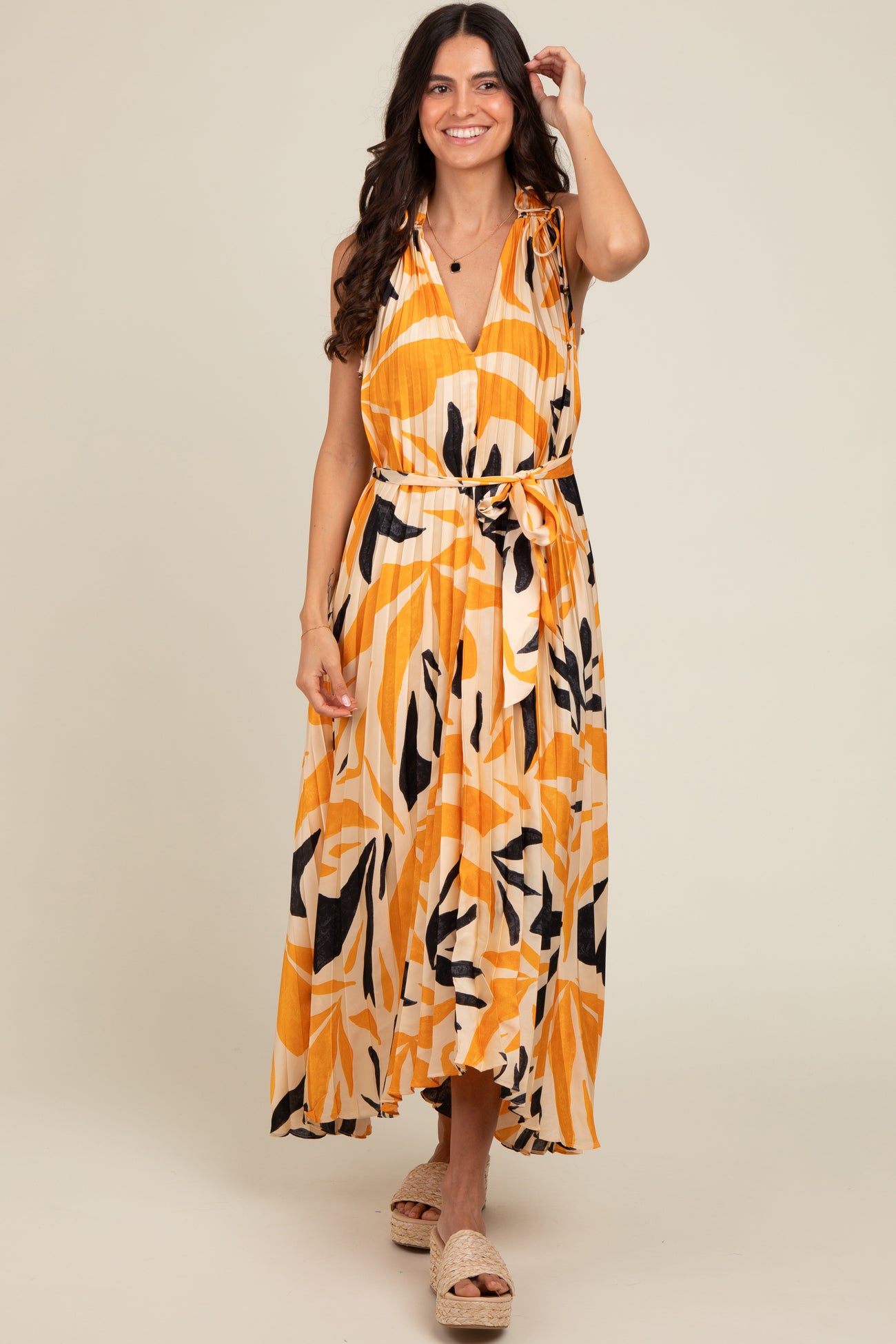 woman wearing a vibrant yellow and black floral print maxi dress with a tie waist and shoulder details