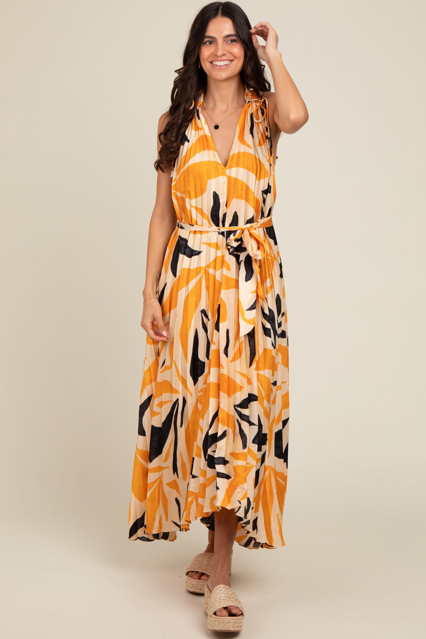 woman wearing a vibrant yellow and black floral print maxi dress with a tie waist and shoulder details