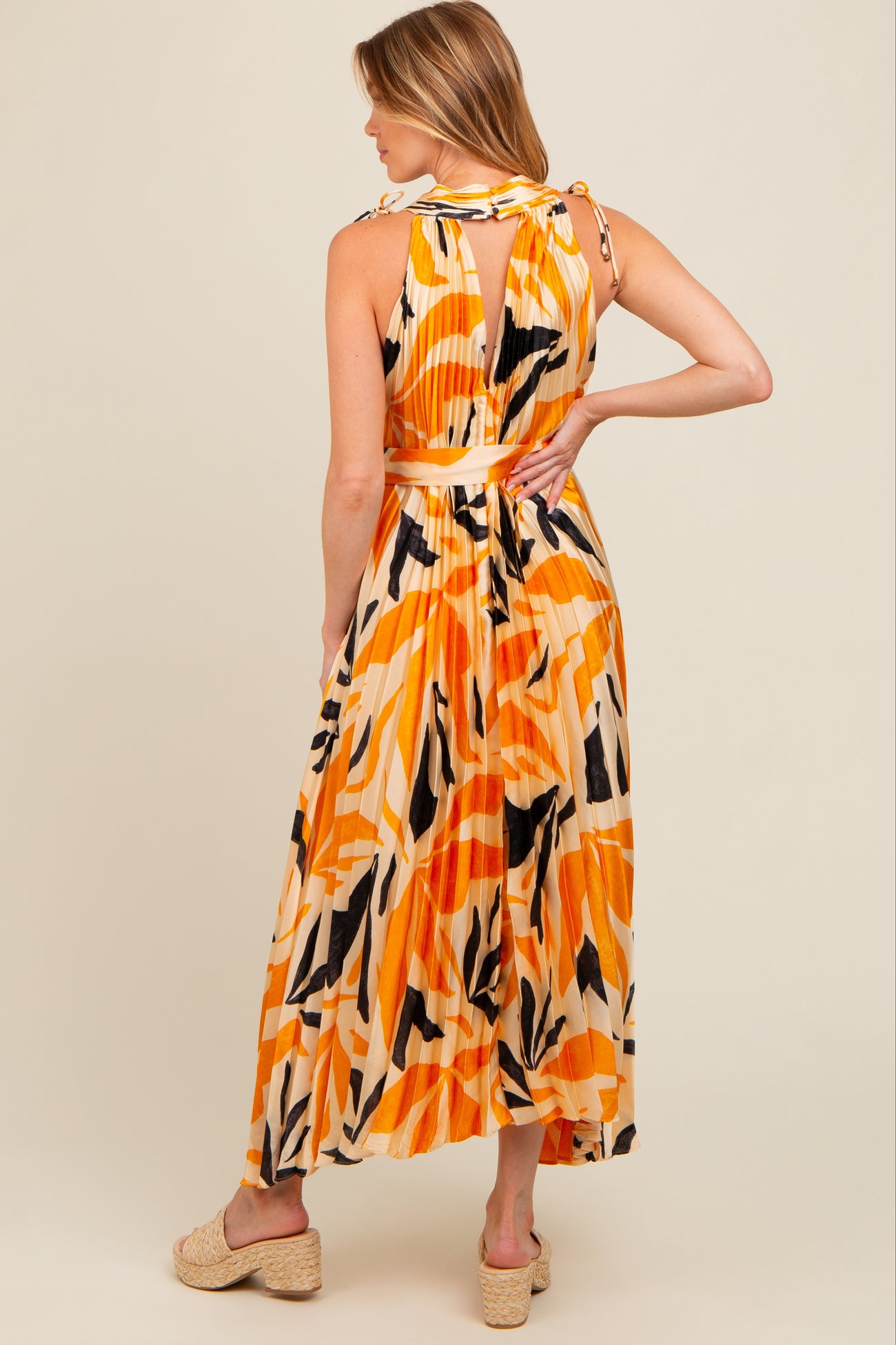 woman wearing a colorful orange and black patterned maternity maxi dress with a tie-back detail