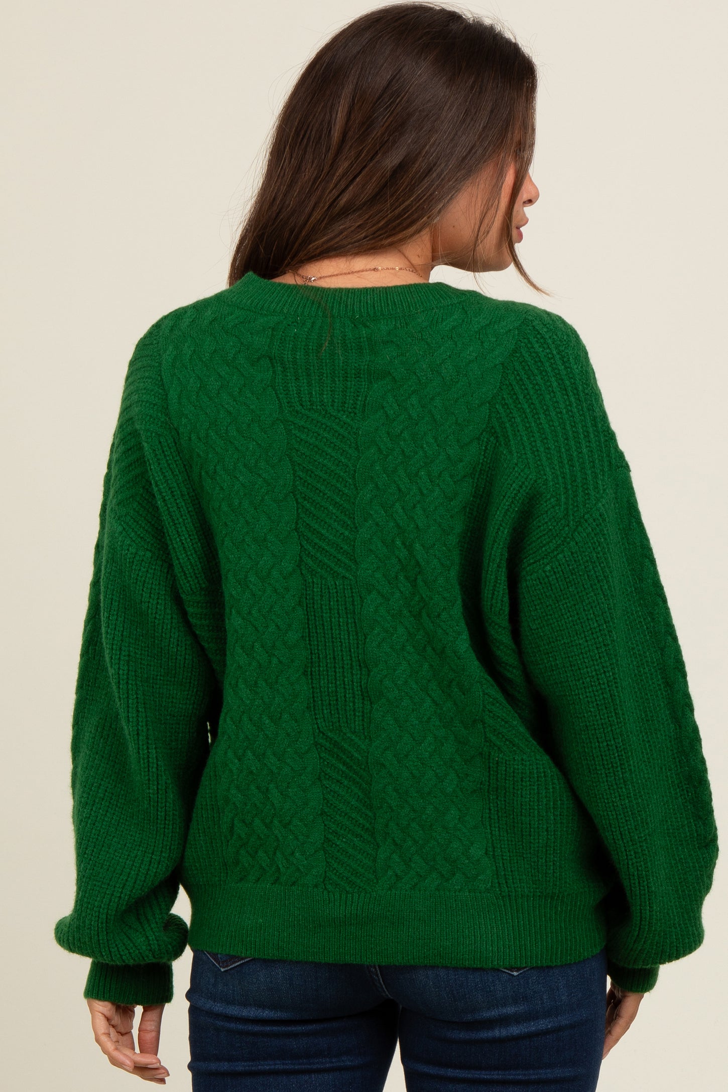 woman wearing a green cable knit maternity sweater with a relaxed fit, view of the back