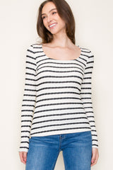 woman wearing a black and white striped long sleeve top with a scoop neck and fitted style, paired with blue jeans