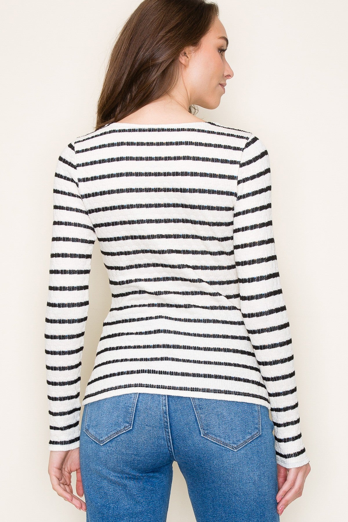 woman wearing a black and white striped long sleeve top with a fitted silhouette and an open back