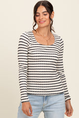 woman wearing a white and black striped long sleeve top with a square neckline and light blue jeans