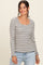 woman wearing a white and black striped long sleeve top with a square neckline and light blue jeans