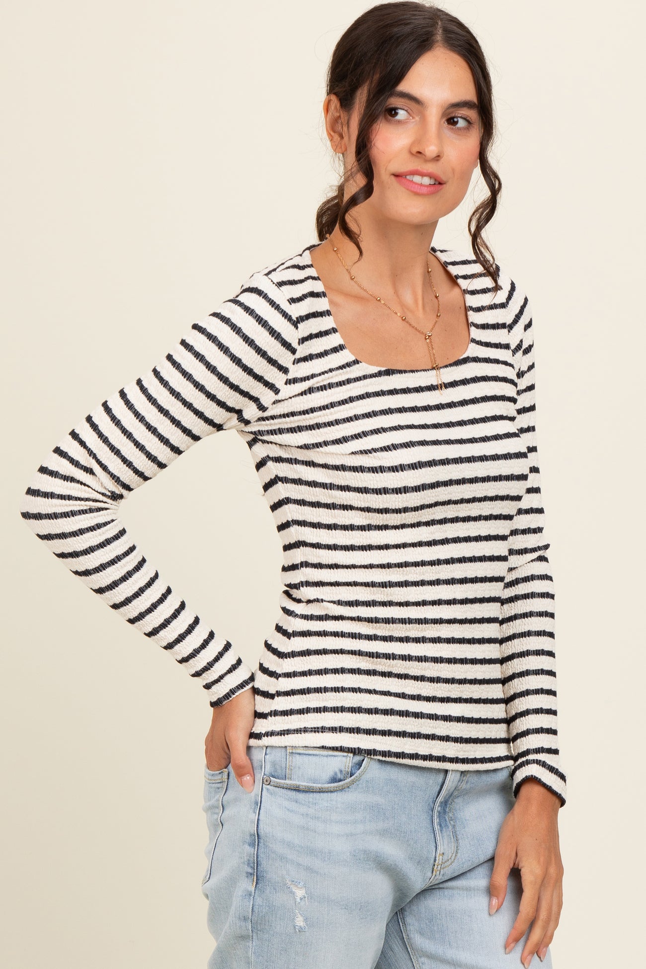 woman wearing a striped long sleeve top with a square neckline and paired with light blue jeans