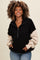woman wearing a black and beige color block zip-up sweatshirt with a relaxed fit and curly hair