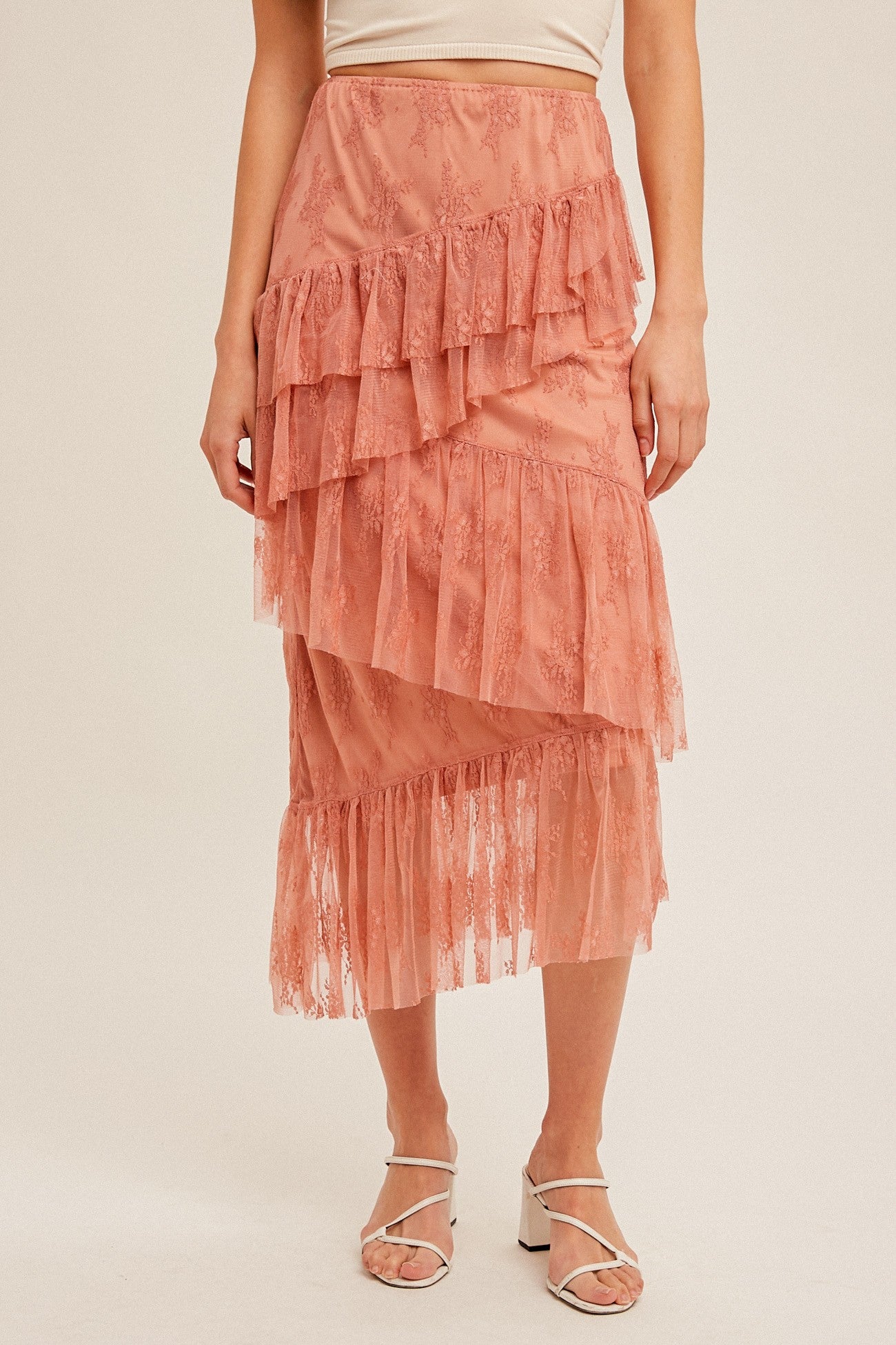 woman wearing a pink tiered lace midi skirt with ruffle details and a fitted waistband