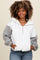 woman wearing a white and gray color-blocked zip-up hoodie with a front pocket and relaxed fit