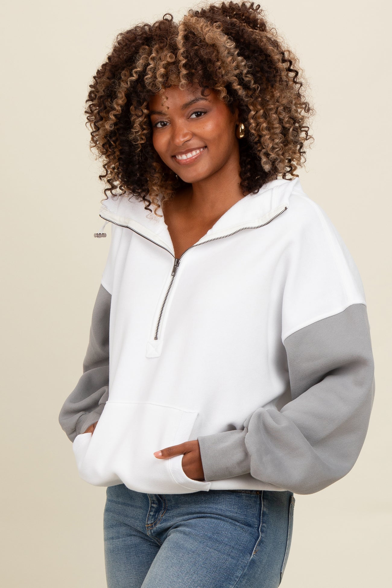 woman wearing a white and gray color-blocked half-zip pullover sweater with a front pocket and relaxed fit