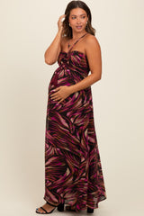 woman wearing a multi-colored floral maxi maternity dress and holding her baby bump