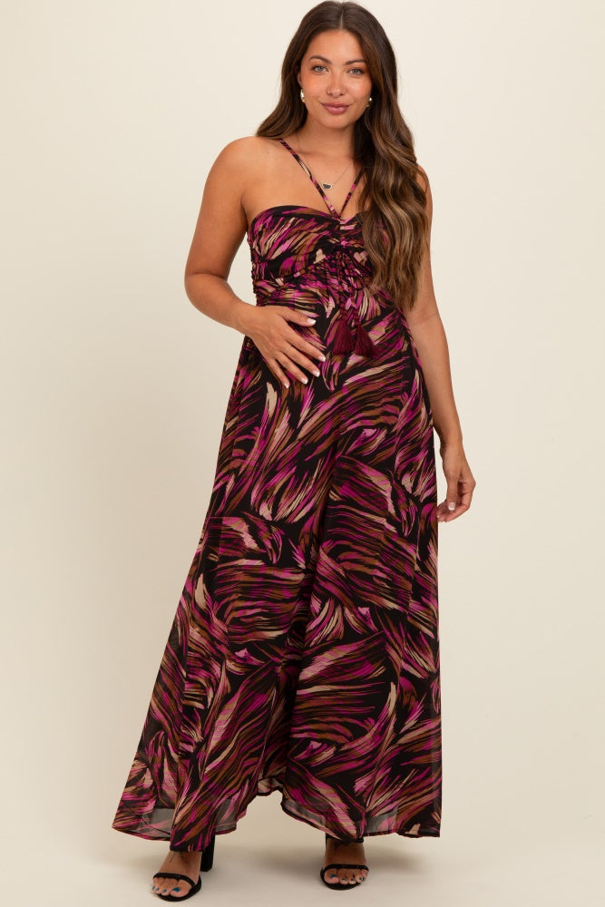woman wearing a black and pink floral print maternity maxi dress with a smocked bodice and adjustable straps, holding her baby bump