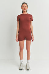 woman wearing a rust short-sleeve bodysuit with a fitted style and standing in neutral footwear