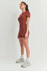 woman wearing a rust-colored short sleeve bodysuit with a fitted style and athletic shoes