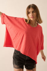 woman wearing a coral oversized t-shirt with short sleeves and black denim shorts