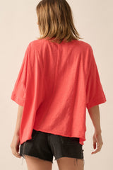 woman wearing a coral oversized t-shirt with short sleeves and a loose fit, paired with black shorts