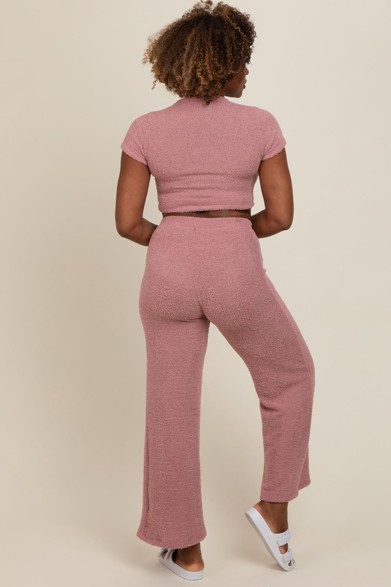 woman wearing a pink short sleeve crop top and matching wide-leg pants, seen from the back