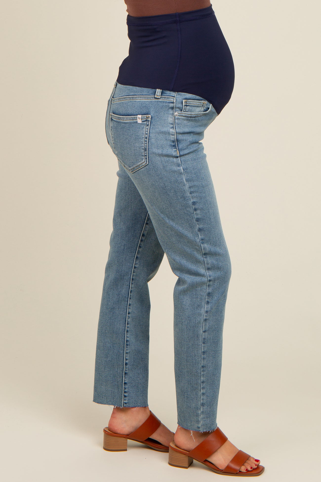 woman wearing light blue maternity jeans with a dark blue waistband and a visible baby bump