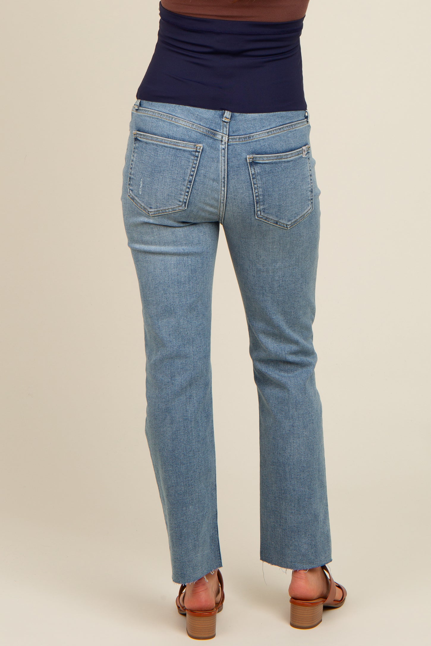 woman wearing light blue maternity jeans with a flared hem and a black top, shown from the back