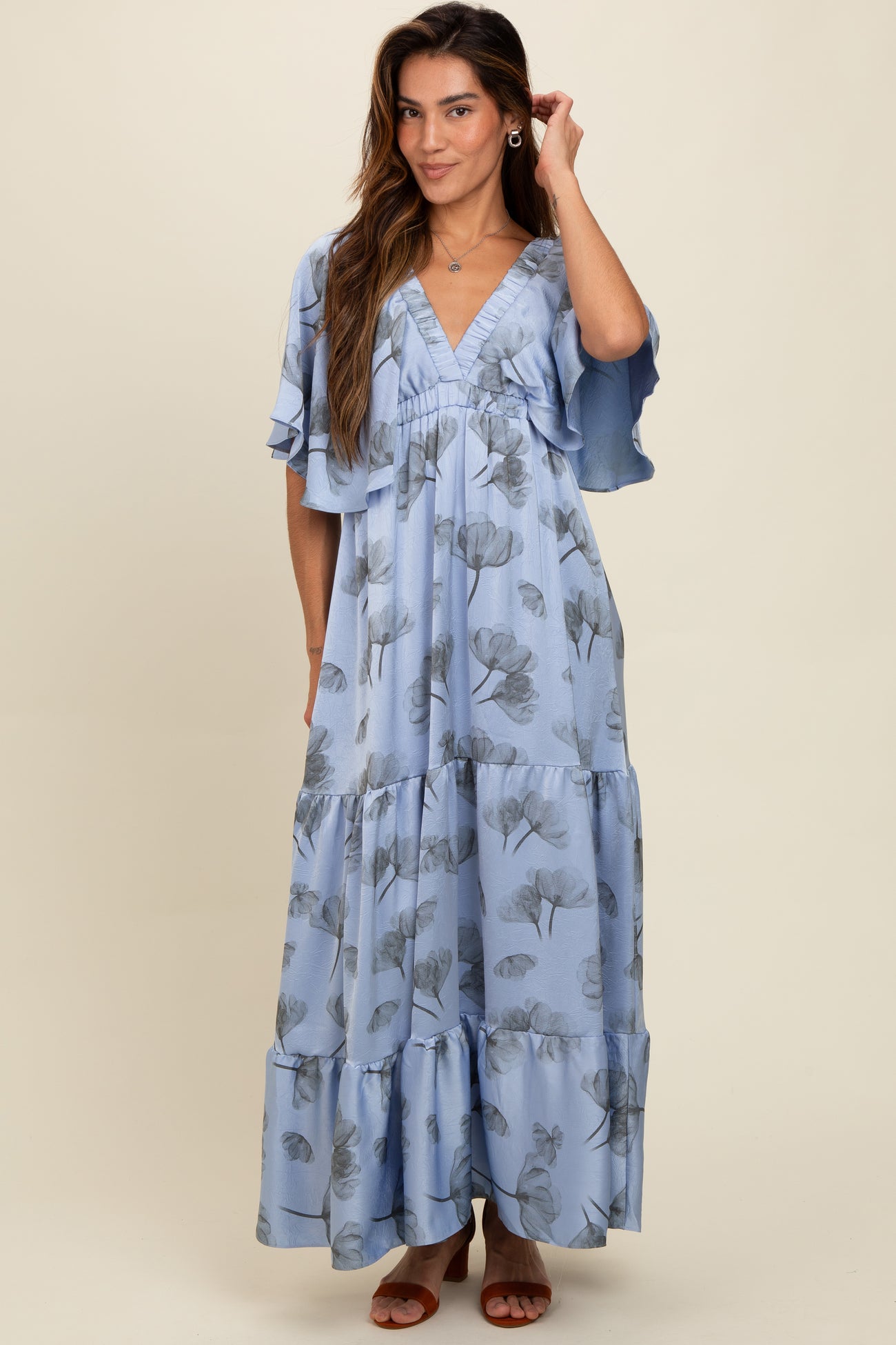 woman wearing a light blue floral maxi dress with flutter sleeves and a deep V-neckline