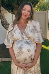 woman wearing a cream floral print maternity dress and holding her baby bump