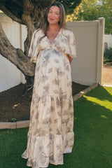 woman wearing a floral print maxi maternity dress with a v-neckline and short flutter sleeves, showing her baby bump