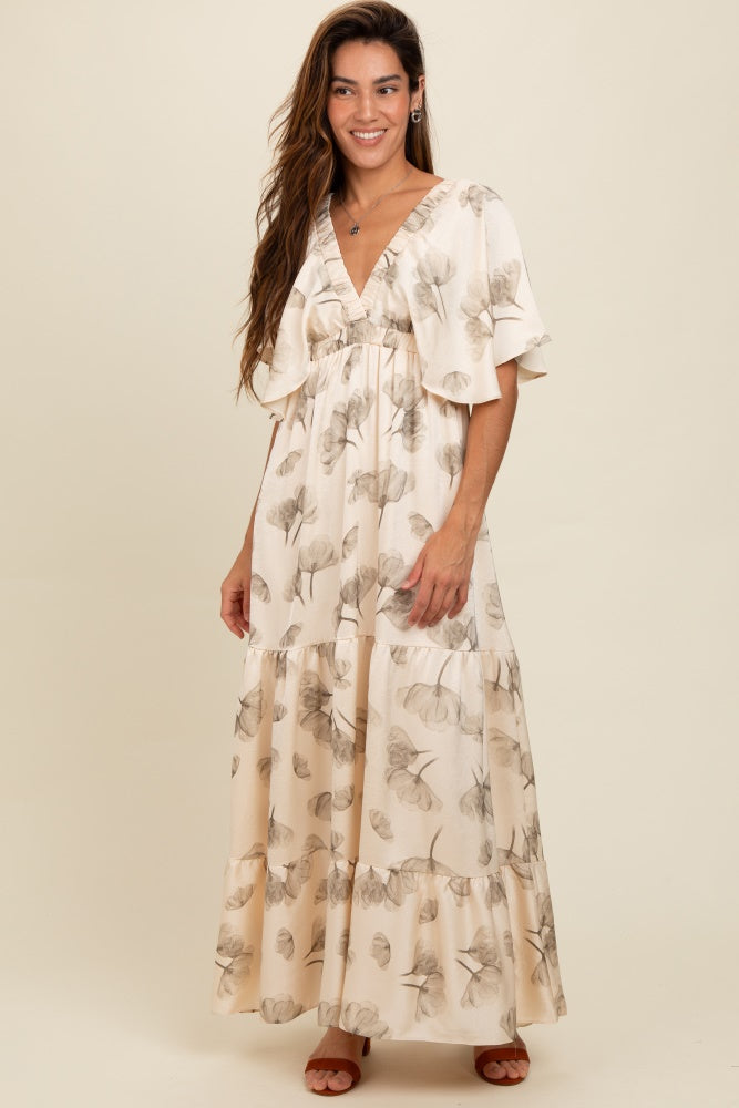 woman wearing a cream floral maxi dress with flutter sleeves and tiered skirt