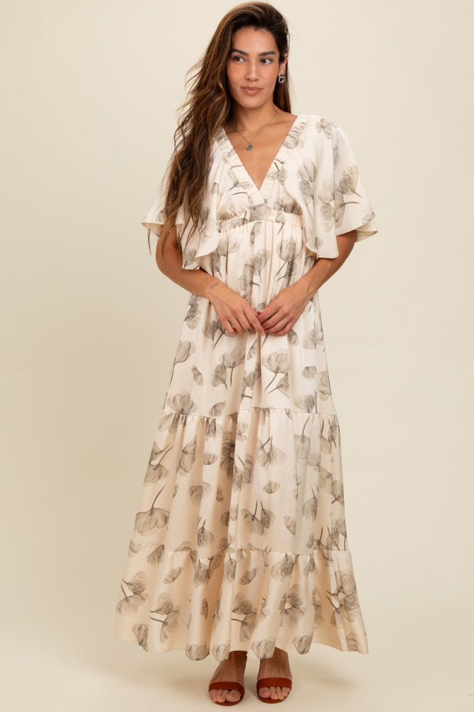 woman wearing a beige floral maxi dress with tiered ruffles and short flutter sleeves