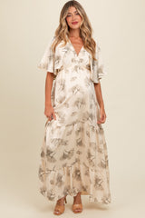 woman wearing a cream floral maternity maxi dress with flutter sleeves and a tiered skirt, showcasing her baby bump