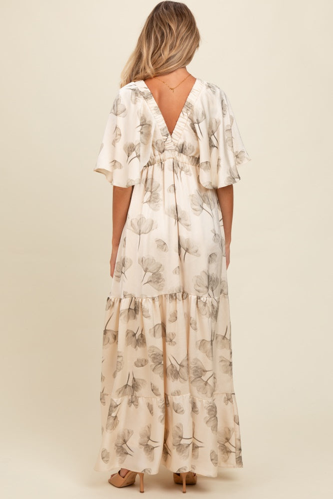 woman wearing a floral print maternity maxi dress with a v-back and flutter sleeves, showing a baby bump