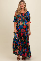 woman wearing a floral print maternity maxi dress with puff sleeves and a smocked waist, showcasing her baby bump