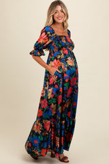 woman wearing a colorful floral maternity maxi dress with puff sleeves and side pockets, showing her baby bump